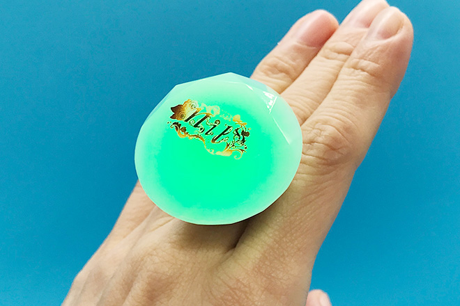 草花に囲まれた文字がきらめくダイヤ型リングライト